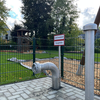 Bild vergr��ern: Der Spielplatz in der Rudersdorfer B�rgerstra�e ist wiederhergestellt, nur der frische Rasen braucht noch etwas Ruhe zum Anwachsen. An den Anlass der Bauarbeiten erinnern die neuen, gl�nzenden Rohre am Stra�enrand: Unter dem Spielplatz haben wir eine unterirdische L�schwasserzisterne eingebaut, damit wir einen gro�en Wasservorrat vor allem f�r Feuerwehreins�tze in der Rudersdorfer Ortsmitte bekommen.