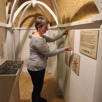 Bild vergr��ern: Museumsleiterin Dr. Corinna Nauck legt in der Kulisse eines Klosters Hand an die Details der Sonderausstellung "Spinnrad, Schwert und Federkiel".